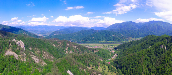 Fototapeta premium Aerial drone panorama above Olt Valley and Cozia Mountains. Small rural villages are found between forested hills of Cozia Mountains.