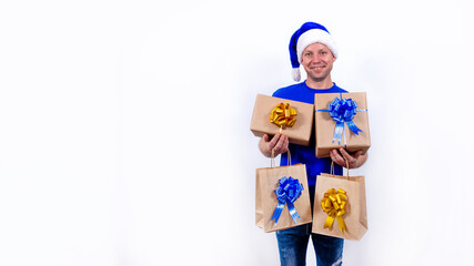 Banner. Happy courier in a blue uniform and Santa hat holds many gifts in his hands. New year and merry Christmas. Man smiles. Secure contactless remote delivery of holiday gifts during coronavirus