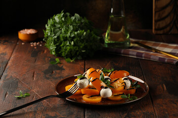 Yellow tomato salad with green basil, mozzarella balls, balsamic vinegar and olive oil, seasoned with black pepper and salt. Delicious and light snack. Vegetarian food.