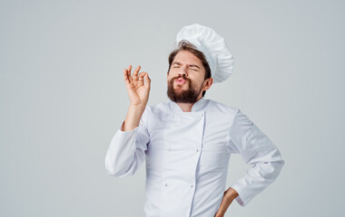 A male chef in a work suit is gesturing with his hands