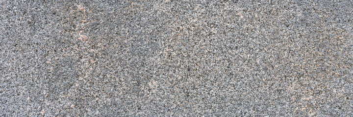 Granite texture. Natural gray granite with a grainy pattern. Stone background. Solid rough surface of rock. Durable construction and decoration material. Close-up.