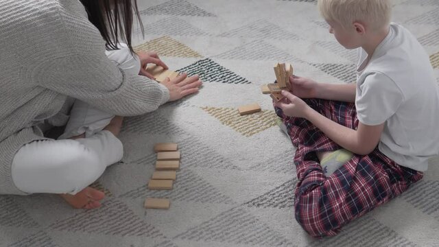 Boy and mom play dominoes at home during lockdown covid-19, woman dials dominoes to start game
