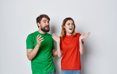 Fototapeta premium young cheerful couple emotions multicolored t-shirts studio isolated background