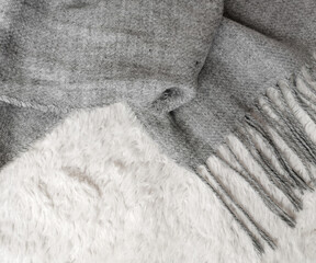 Woolen scarf of grey color on white background, top view, space for text. Winter clothes