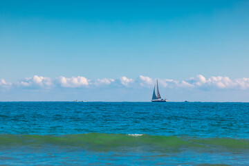 Obraz premium Sailboat over blue waves and sunny sky. Sea and sailing wind boat