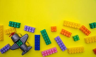 The plane is made of designer parts and cubes are scattered on a yellow background.