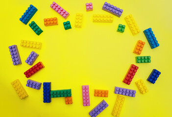 Constructor details are scattered on a yellow background. Multi-colored construction blocks.