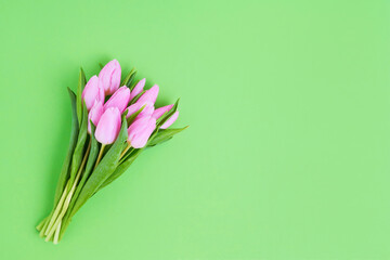 Pink tulips bouquet on green background. Top view, copy space