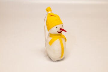 Christmas toy snowman with a red nose in a yellow hat and a scarf on a white background