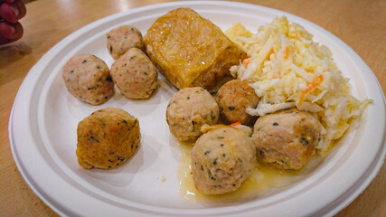 Lunch at a roadside cafe. Scrambled eggs, croquettes, meatballs, salad on a disposable paper plate.