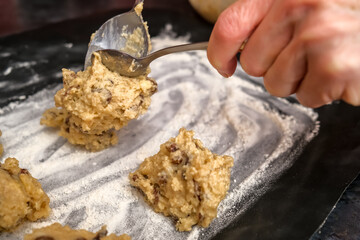 Norwich, Norfolk, UK – December 06 2020. Illustrative editorial photography of an unidentifiable home baker spooning cake mixture on to a lined and floured baking tray