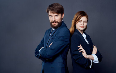 Business successful people in suits stand with their backs to each other on a gray background confident look