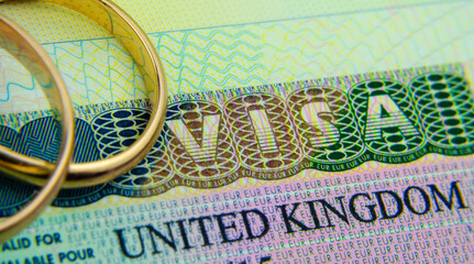 UK entry visa sticker in a passport and the rings placed on top. Concept for Partner and Spouse visa UK.