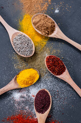 Various spices in spoon or bowl on dark rustic table, spice background