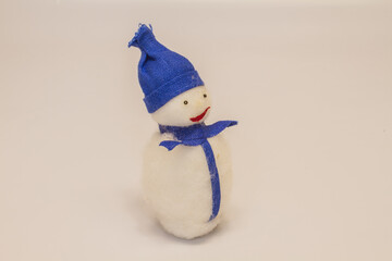 white toy christmas snowman without red nose in purple hat and scarf isolated on white background