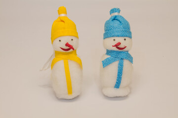 a couple of christmas toys two snowmen with red noses in yellow and blue hats and scarves isolated on white background