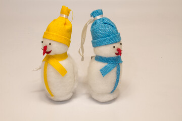 a couple of christmas toys two snowmen with red noses in yellow and blue hats and scarves isolated on white background