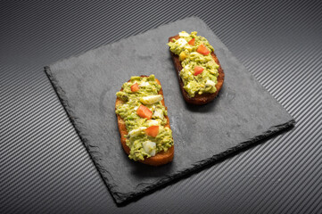 Two sandwiches with avocado and egg salad. Sandwiches on a black background.