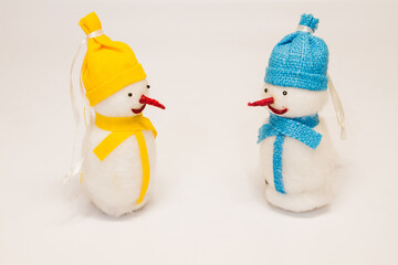 a couple of christmas toys two snowmen with red noses in yellow and blue hats and scarves isolated on white background
