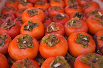 Background of ripe persimmons. Persimmon fruits are sold in the market. Persimmon is a delicious and healthy fruit. Fig persimmon close-up lies in rows.