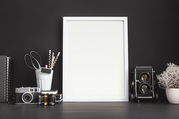 Mock up photo frame on a black wall with medium format camera.