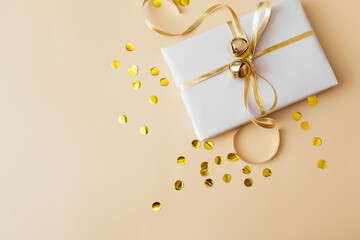 Christmas presents and gifts and gold confetti on beige background. Merry christmas, New Year holiday concept. Flat lay, top view, copy space.
