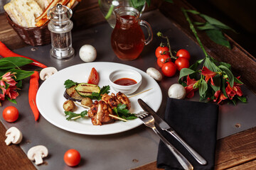 Barbecued marinated turkey or chicken meat shish kebab skewers with ketchup sauce and grilled vegetables on rustic wooden table background