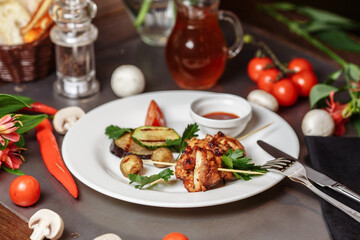 Barbecued marinated turkey or chicken meat shish kebab skewers with ketchup sauce and grilled vegetables on rustic wooden table background