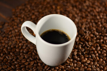 Cup of coffee and roasted coffee beans on a wooden table