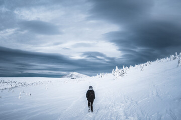 Fototapeta na wymiar Woman climbing on the mountain, woman with a backpack walking on snow, Krkonose, Czech republic
