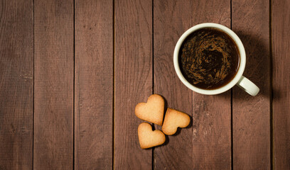 Hear shaped cookies and a cup of coffee on wooden table. Copy space.