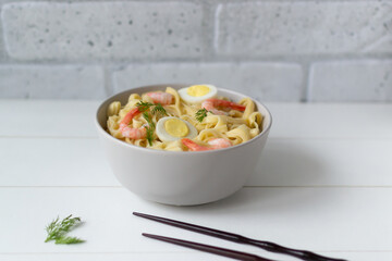 Natural homemade noodles with shrimps and quail eggs on a light background. Horizontal orientation. Copy space. Selective focus.