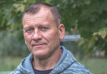 portrait of handsome attractive middle aged man looking with smile, against background of autumn...