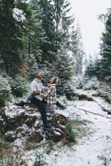 Naklejka na ściany i meble Funny couple eating snow sitting on rock in snowy forest