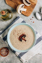 Mushroom cream soup in blue bowl on light gray background.