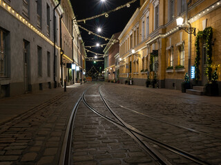 Naklejka na ściany i meble A tranquil scene of an empty European alley with tramway tracks on the stone pavement.