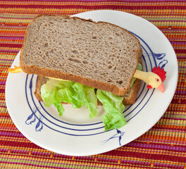 Rubber chicken sandwich with lettuce on plate.