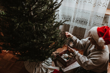 Christmas tree decorating. Holiday time. Lights, ornaments, vintage retro decor. Green fur tree. Merry Christmas, Happy New Year. Authentic tree ornaments. Holiday is over. Pack stuff to the boxes.