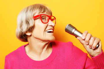 lifestyle and people concept: Portrait of funny grandmother holds up the microphone stand and sings
