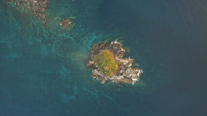 Fototapeta na wymiar Top down of rock island with green peak aerial. Ocean waves crash on cliffs. Nobody tropic nature seascape at summer day. Epic sea bay with greenery isle. Cinematic Philippines landscape