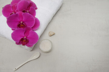 Red branch orchid flower on white towel with stones, candle ,salt in bowl with copy space