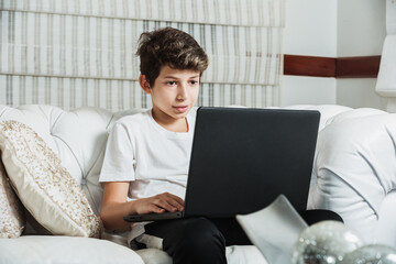 Fototapeta premium young latin american man watching a video lesson on the computer sitting on the sofa at home