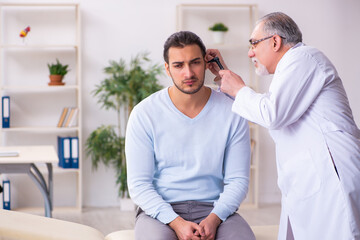Obraz premium Young sick man visiting old doctor otolaryngologist