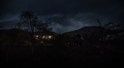 Mountain night landscape of building at forest at night with moon or vintage country house at night with clouds and stars. Summer night.