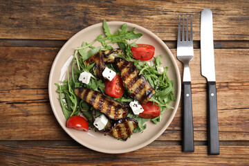 Delicious salad with roasted eggplant, feta cheese and arugula served on wooden table, flat lay