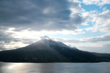 初雪の桜島と降り注ぐ朝日