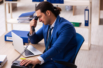 Young handsome employee sitting in the office