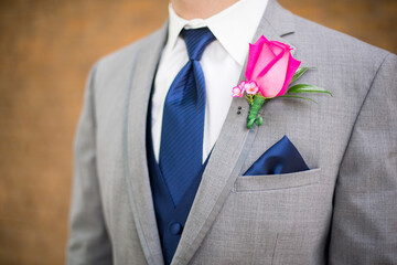 gray suit jacket with navy tie and hot pink rose
