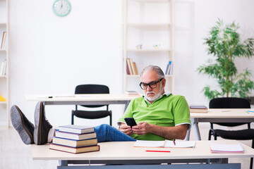 Old male student preparing for exams in the classroom