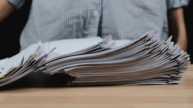 Working hard and  Work overload concept, Business woman hand holding Stacks overload document paper files putting on the table. Close up.